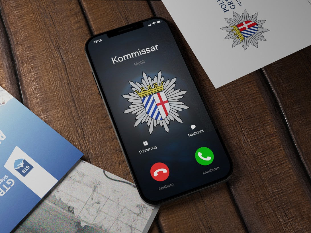 Handy mit Anruf vom Kommissar neben Unterlagen der Polizei Gretenburg und der GTB-Arena